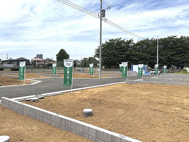 【【現地全景】】爽やかな風が渡り、各棟に陽光を導くゆとりあるランドプランです。駐車スペースを全棟に配置。前面道路とフラットで、お車や二輪車の入出庫もスムーズに行っていただけます。/2026年5月撮影