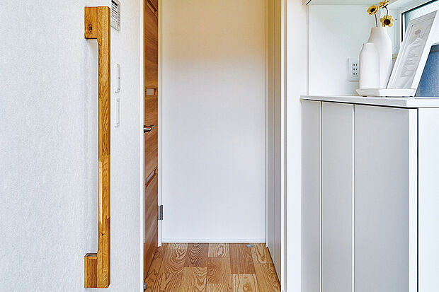 【【玄関手すり/銘木無垢ハイジェニック】】銘木の心地よい感触を楽しめる手摺を玄関に設置しています。しっかり握ることができるので、靴の脱ぎ履きもしやすく安全です。