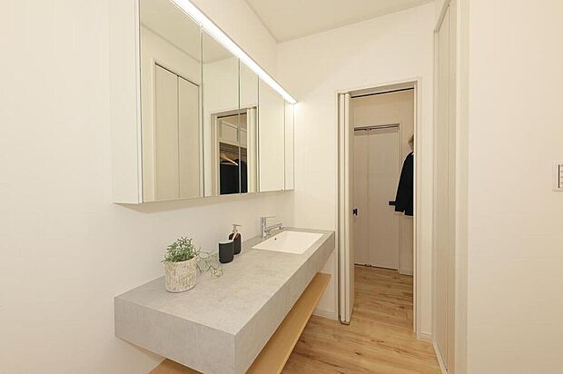 【洗面室/当社施工例】
フロートタイプの洗面台がホテルライクな雰囲気。ご家族で並んで身支度ができるワイドサイズです。ファミリークローゼットに隣接しているので、洗濯物をそのまま掛けて収納できます。