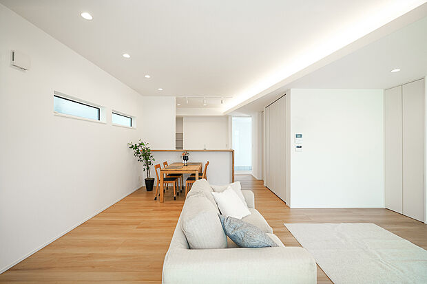 【日進市梅森町新田 モデルハウス】20帖のLDKに大きな窓から光が広がり、下がり天井と高い天井が立体的な奥行きをつくる空間。間接照明とダウンライトが陰影を整え、家族が自然と集まる、上質で開放的なリビング