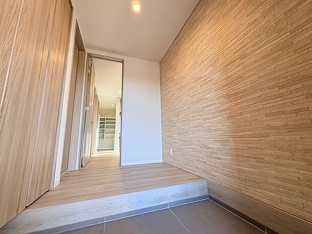 【玄関ホール】質感豊かなアクセントウォールが印象的な玄関。奥行きを感じる設計で、訪れる人をやさしく迎えます。