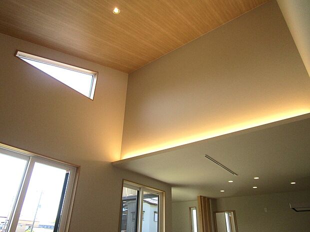 【吹き抜け（内観）】間接照明が映し出す木目の風合い。勾配天井が創る心地よいくつろぎの住まい。
