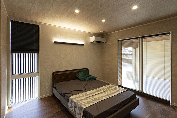 【1階約7.5帖主寝室/A号地モデルハウス】間接照明による光の陰影が美しく、上質なクロス使いで特別感あるデザインの主寝室。ダウンライトが空間全体をスッキリとみせ、リラックスタイムへと誘います。