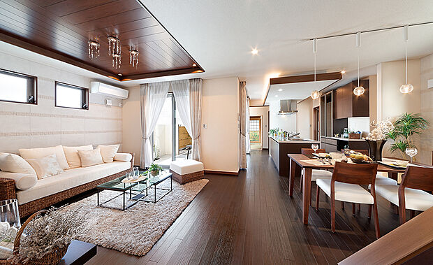 【当社施工例】
広々とした開放的なLDK。落ち着いた色合いのフローリングが穏やかな空間を演出します。折り上げ天井や家具の色合いを揃えることで高級感も生み出しています。