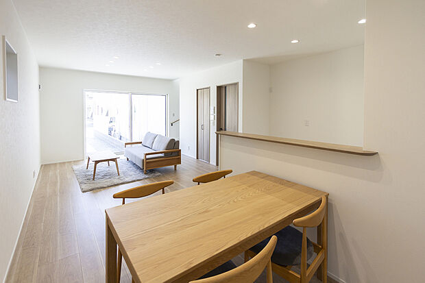 【【1階約17.8帖LDK/A号地】】ダイニングやキッチンのどこにいても視界が抜け、ホワイト×明るいトーンの木目のフロアや建具によりやわらかなナチュラルテイストに。リビング階段下を利用した収納を備えています。