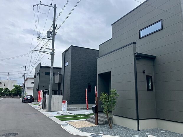 グレー基調の洗練された外観が並ぶ街並み。前面道路はゆったりとして駐車スペースが確保され、植栽のある落ち着いた導線で暮らしやすさを感じられます。駐車2～3台対応可能です。