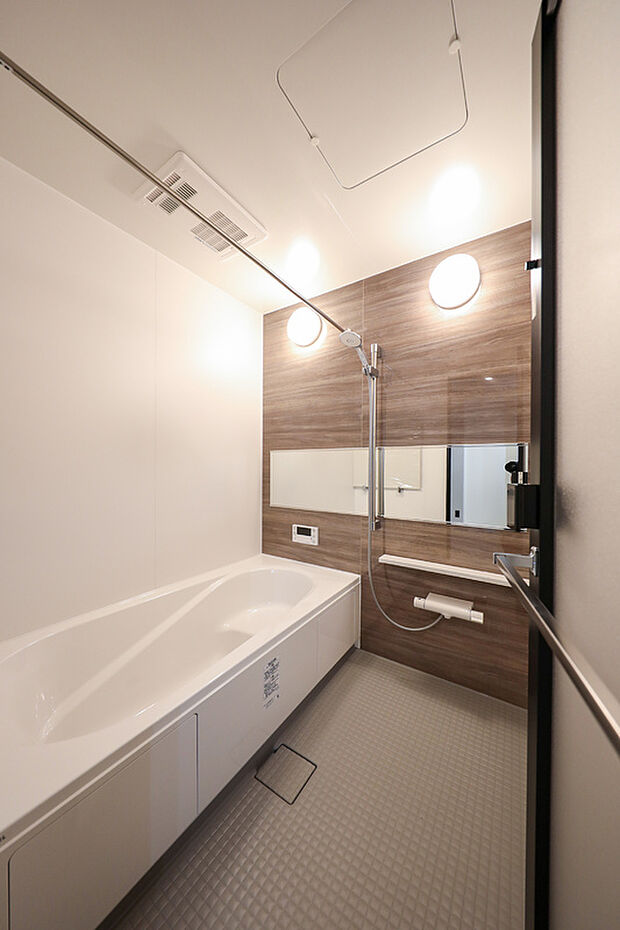 【【施工例】浴室】温かみのある木目調の壁で、毎日のバスタイムが特別になるホテルライクな浴室です。シャワー用スライドバー、ワイドミラーを採用しました。