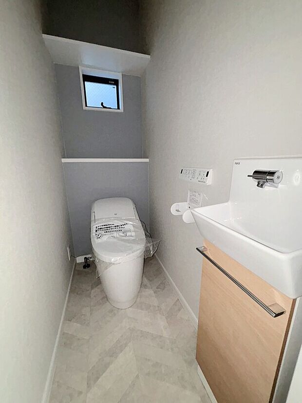 【【施工例】トイレ】手洗い台下に収納を設け、ストックや掃除用品もすっきり収まる設計。使い勝手とすっきりとした印象を両立しています。