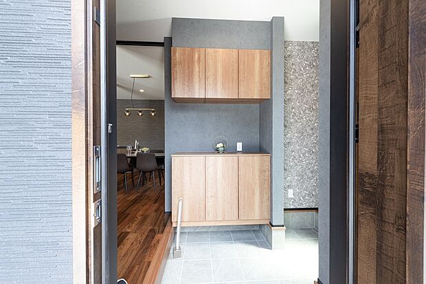 【【1階玄関/D号地モデルハウス】】濃グレー×しっかりと落ち着いたフロアにより、高級感あるモダンなエントランスが毎日の帰宅やゲストをお出迎え。土間収納は玄関から靴のままで出入りができ、靴だけでなくアウトドア用品なども収まります。