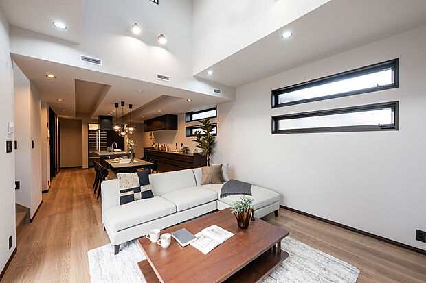 【A号棟:リビング】温かみのある照明と木の質感が調和するリビング。吹抜けの開放感と陰影が生み出す上質な空気に包まれ、家族の時間がゆったりと流れます。