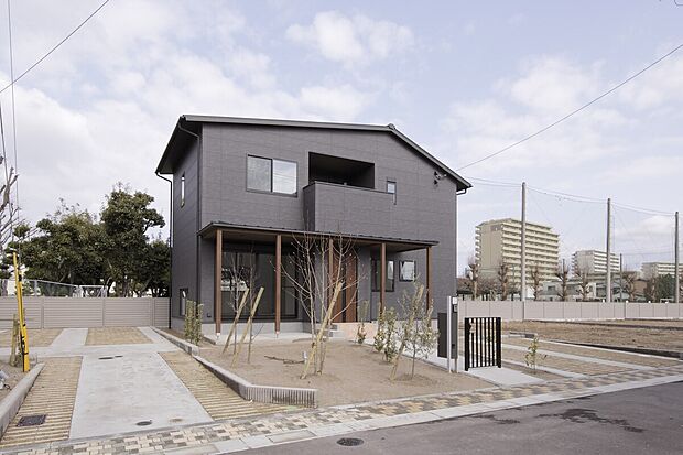 【7号地外観】黒を基調としつつ自然なムラがはいる落ち着いた印象。リビング・ダイニングとポーチ下半屋外の土間テラスから、庭へとつながる一体感のある空間のお住まいです。