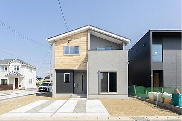 【7号地：個性が光るアシンメトリーな屋根の外観】明るい木目調とグレーを組み合わせた、カフェのようにナチュラルで可愛らしい佇まい。斜めにカットされた特徴的な屋根が、デザイン性をぐっと高めています。