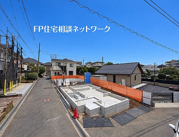 青空に映える建築中の現地。道路の先まで住宅街が続き、新しい暮らしを思い描ける風景です。