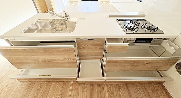 【内観】【キッチン収納】類似内観仕様  木目調の面材が映える対面キッチン。引き出し式収納で調理道具もすっきり整理でき、家事動線にも配慮。毎日の料理が快適になる、機能性とデザイン性を兼ね備えた空間です。