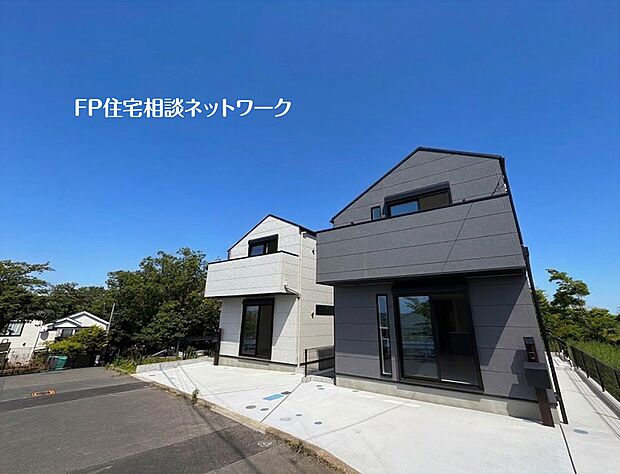 【現地外観写真】青空に映える、モダンで美しい二棟の新築住宅。陽当たり良好なこの場所で、新しい暮らしの物語がここから始まります。