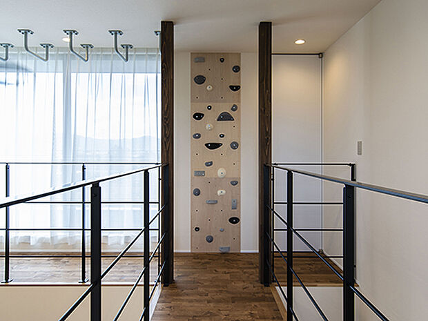 【【プラン例】】2つの吹き抜けに挟まれたブリッジの先に、ボルダリングと雲梯を設置。優しい色合いなので悪目立ちしない。室内アスレチックで家の中でも楽しみながら体力づくり。