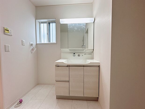 【【２号棟：洗面台】】ボウルとの一体型成形で継ぎ目のないハイバックガードと壁出し水栓は、汚れがたまりにくく、毎日のお手入れが簡単です。使いやすい収納も充実。(2026年１月26日撮影）