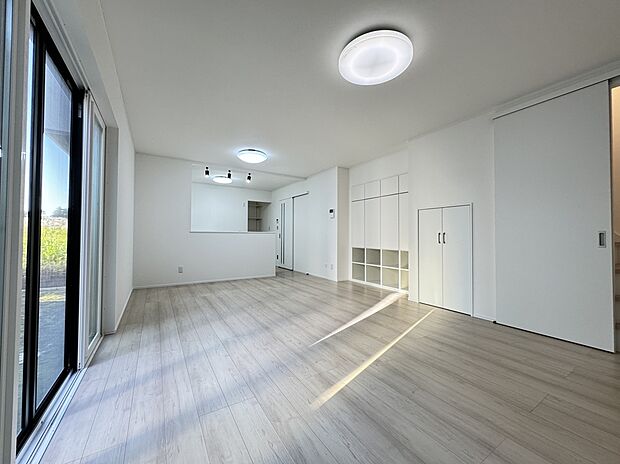 【1号棟　LDK】柔らかな光が回る、清潔感あふれるLDK。明るい色味のフローリングが、家族の団らんを優しく包み込みます。機能的なリビング収納も備えた、スッキリ暮らせるお住まいです。