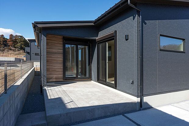 【４号棟】リビングからフラットに続くタイルテラスは、内と外をゆるやかにつなぐ開放的な空間。木目調のアクセント壁が温かみを添え、休日のブランチやティータイムを贅沢に演出する、平屋ならではの寛ぎの場です。