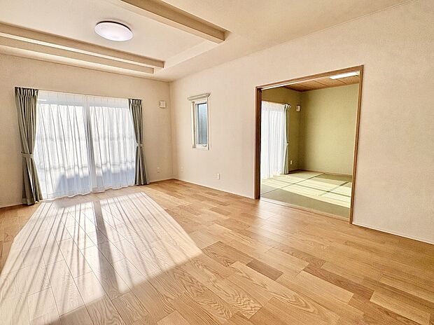 【陽射し差し込むリビングと隣接和室】大きな掃き出し窓から光が入るナチュラルなフローリングのリビング。注文住宅ならではの上質な床材は、家具などのインテリアも引き立てます。引戸で続く8帖の和室と合わせると31帖の大空間が生まれます。