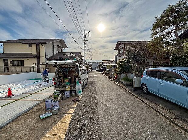 【前面道路含む現地写真】第一種低層エリアならではの広い空と陽光。前面道路は約5mとゆとりがあり、お車の出し入れもスムーズです。交通量が落ち着いた閑静な住宅街で、静かな暮らしが叶います。