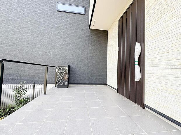 【現地外観写真】洗練されたモダンな外観が印象的な玄関アプローチ。明るいタイルとゆとりある空間が、ご家族やゲストを心地よくお迎えします。宅配ボックス完備