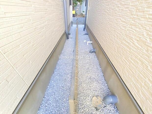 建物間に設けられたメンテナンス通路で、排水設備や配管が整備されています。