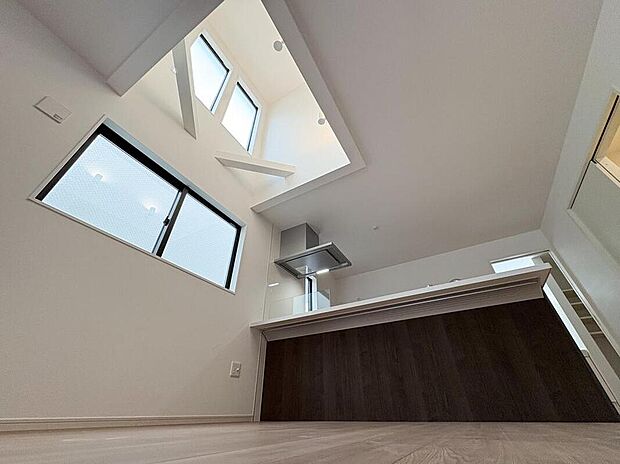 吹き抜けから光が降り注ぐ開放的なキッチン。家族の気配を感じながら料理を楽しめる贅沢な空間です。