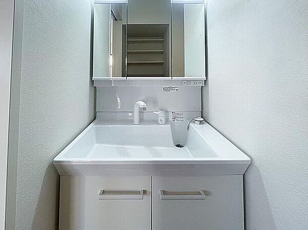 【洗面所】清潔感のあるホワイト調で統一されたプライベート空間は、身だしなみチェックや肌のお手入れに最適です。大きく見やすい三面鏡で清潔感ある洗面台は収納も多く、コスメ等もスッキリと仕舞えます。