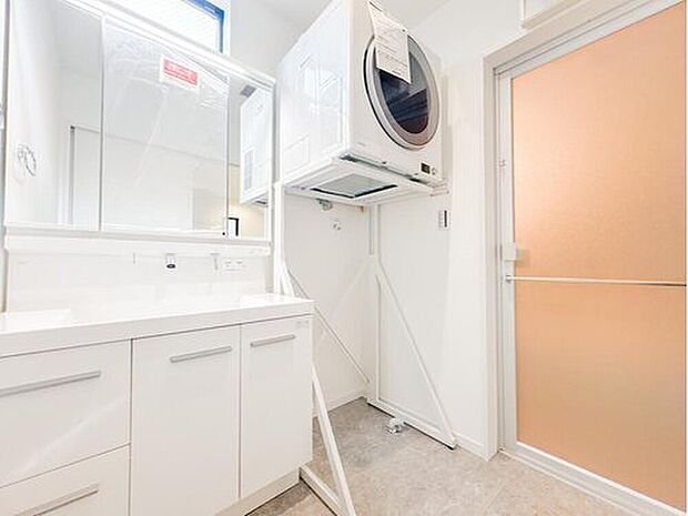 【洗面台・洗面所】清潔感溢れる白の洗面化粧台は、収納力豊富な三面鏡付き。話題のガス衣類乾燥機「乾太くん」を完備し、家事時間を大幅に短縮できます。小窓からの採光もあり、毎日の身支度や家事が心地よく捗る機能的な空間です。