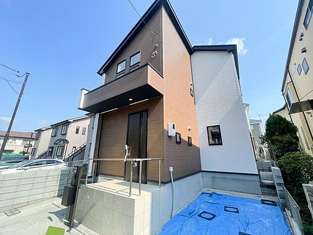 【現地外観写真】落ち着いた木目調と、清潔感あふれる白のコントラストが美しいデザイン住宅 。第一種低層住居専用地域の穏やかな街並みに映える、モダンな外観が魅力です 。