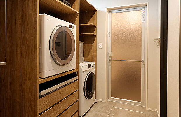 【名古屋守山お泊りハウス 内観】1階床面積/73.13m2(22.12坪)2階床面積/57.75m2(17.46坪) 延床面積/130.88m2(39.59坪)。無機質になりがちな、ガス衣類乾燥機とドラム式洗濯機。専用ラックを設けてスッキリと収納したプラン。