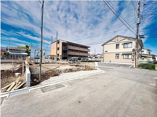 【前面道路含む現地写真】青空の下、1号棟の建設が進む現地です。周辺には住宅が広がり、お子様の成長を見守る穏やかな住環境が魅力。家族の未来を育む場所です。

