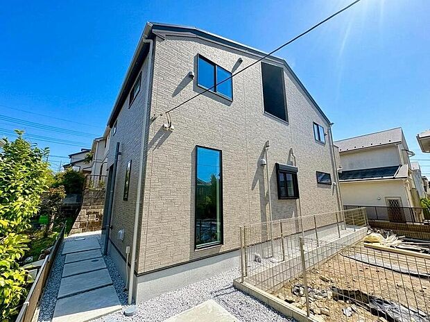 【現地外観写真】陽光降り注ぐ青空の下、洗練されたデザインが目を引く住まい。新しい暮らしへの期待が高まる、開放感あふれる外観です。