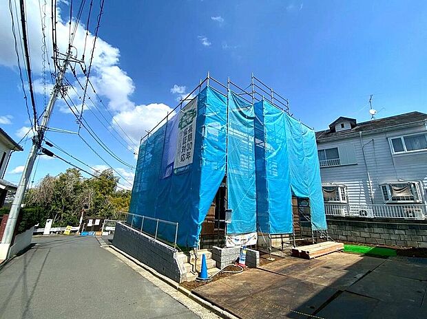 青空に映える建設中の邸宅。隣地との間隔が保たれた53坪超の敷地は開放感抜群です。周囲の緑も心地よく、四季の移ろいを感じながら家族でゆったりと過ごせます。