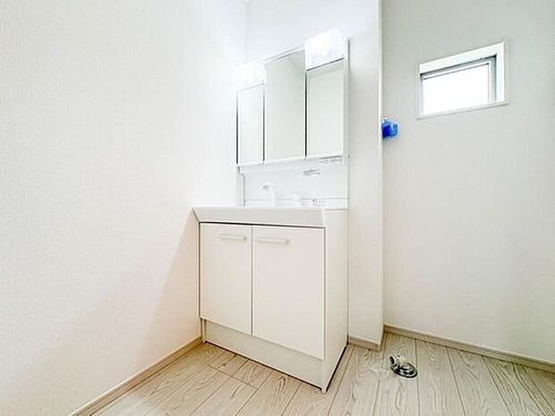 【2号棟【三面鏡洗面化粧台】】ミラーを手前に引けば、楽な姿勢で髭剃りやメイクができます。合わせ鏡にすればヘアスタイルのチェックもラクラク。洗面化粧台のミラー裏にはたっぷり入る収納スペースを設けています