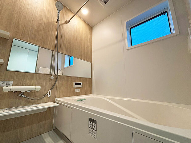 【 浴室　A号棟現地写真】■リクシル　システムバスルーム「AX」。フロアはスポンジが奥まで入り掃除がラクラク。また独自の断熱層を使用しているため冬場でも冷やっとしません。