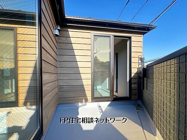 【バルコニー】木目調の外壁が美しいプライベートバルコニー。高い壁に囲まれながらも、青空の下で光と風を感じられます。洗濯物干しはもちろん、カフェタイムにも最適です。