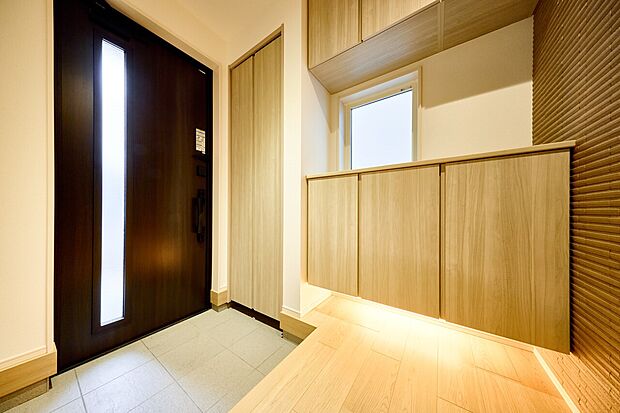 【玄関】アクセントウォールや間接照明を設え、お客様をお迎えする玄関の表情を豊かに彩ります。(2号棟)