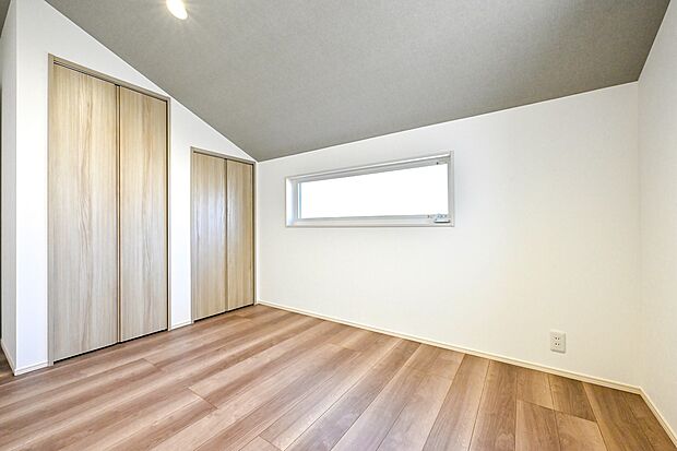 【リビング以外の居室】屋根の角度を生かした開放感あふれる勾配天井とアクセントクロスを施した2階洋室。子供部屋や書斎スペースにもピッタリ。(1号棟)