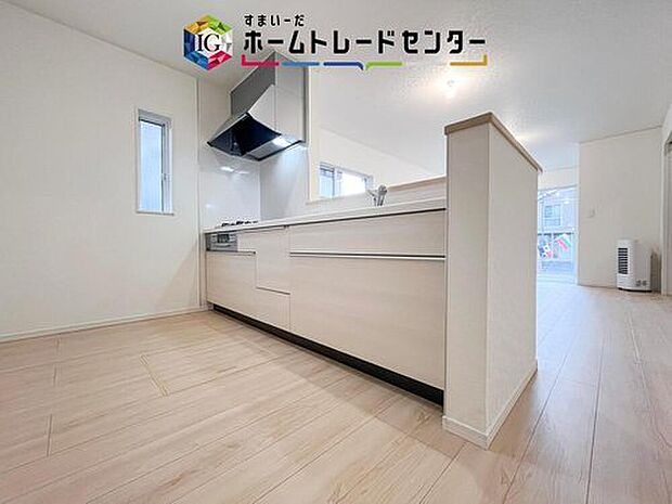【【システムキッチン】】幅広引き出し収納とレンジフード付きの対面キッチン。小窓で採光が確保され、リビングとつながる開放的な配置です。