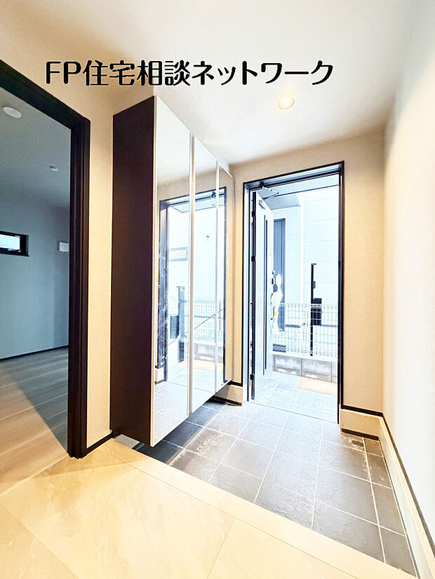 【スタイリッシュな玄関】鏡面の靴箱で空間が広く、明るく。モダンなタイルとダークフレームの組み合わせがスタイリッシュ。収納力とデザイン性を両立した玄関です。