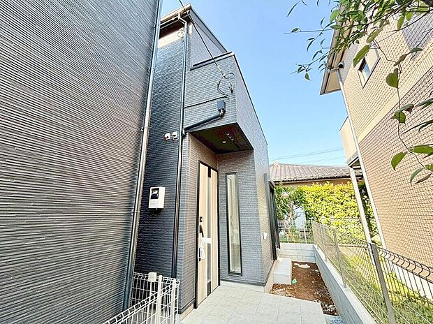 【現地外観写真】住まいの第一印象を彩る、洗練された玄関アプローチ。落ち着いた外観デザインが上質な雰囲気を演出し、帰るたびに心地よさを感じられる住まいです。