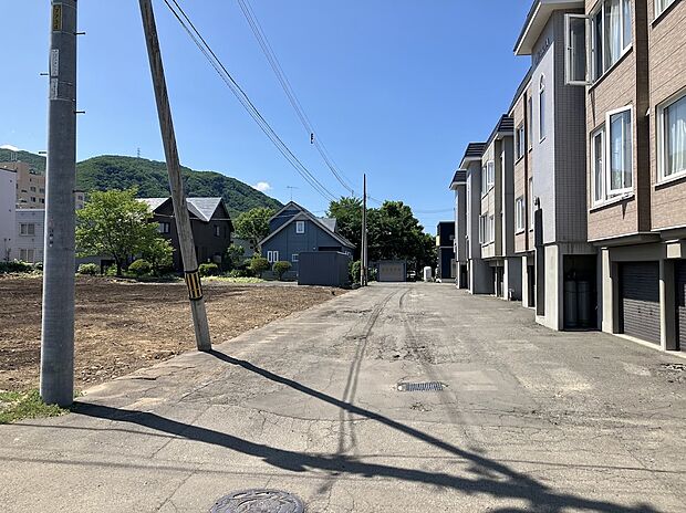 【現地写真】
幅員6m以上の広い道路に面し、陽当たり良好で開放感がございます。見通しが良く、比較的車通りも少ないため、お車の出し入れもしやすく、毎日の外出も快適です。
（2026年8月撮影）
