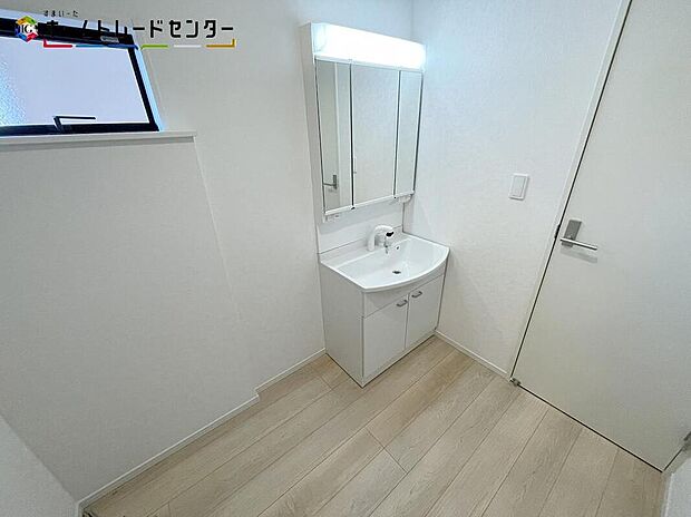 【洗面台・洗面所】２号棟
女性にはうれしい３面鏡化粧台。鏡の裏が収納になっている機能的なタイプです。窓が備えられております。毎朝の身支度も、陽の光差し込む明るい空間で、快適にお使い頂けそうです。