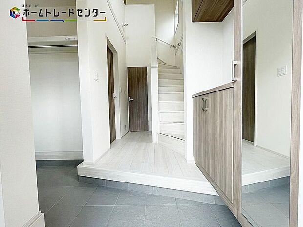 【1号棟玄関】吹抜けの高い天井と、光溢れる明るいエントランス。毎朝の「いってきます」が爽やかに変わり、一日の始まりを気持ちよく後押ししてくれます。デザイン性と実用性を兼ね備えた、自慢したくなる玄関です。