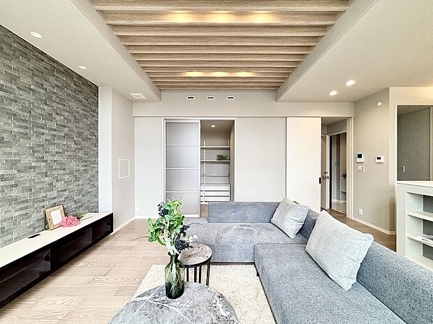 【【4号棟】リビング】素材感の感じられるグラビオエッジのアクセントウォールとルーバー天井で、スタイリッシュな空間となりました。ルーバーと間接照明で奥行き感が強調され、空間に立体感を持たせることができます。