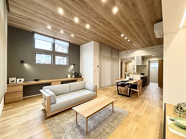 【13号棟】天井高3mがもたらす圧倒的な開放感と、採光豊かな4連窓による明るさが魅力。木目の天井と、アクセントウォールが調和し、洗練されながらも温もり溢れるリビング空間を演出します。