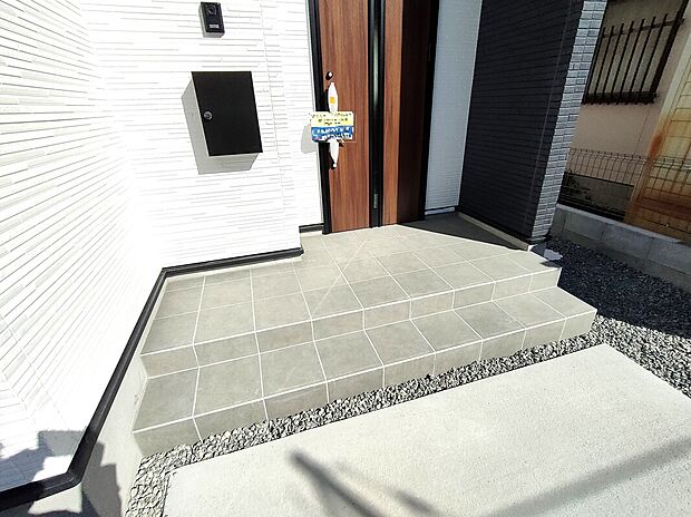 【玄関エントランス】タイル貼りの玄関アプローチは、清潔感と高級感を演出。ポストやインターホンもスマートに配置され、来客時の印象も良好。段差も少なく、毎日の出入りが快適な設計です♪