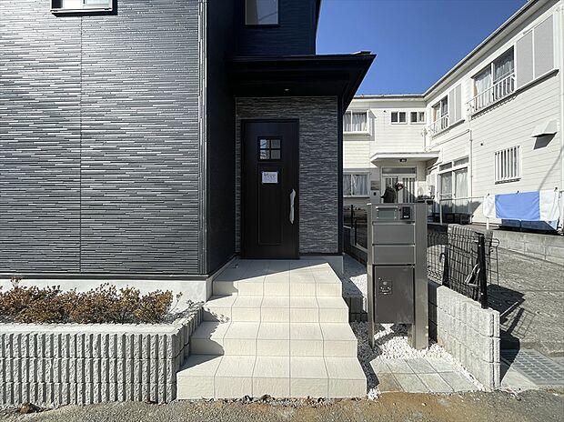 【玄関】落ち着いた色合いの玄関が、帰るたびにほっと迎えてくれる新築戸建て。段差の少ないアプローチで、毎日の出入りも安心。住まう人にやさしいお家です。